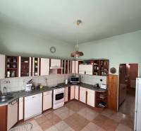 A kitchen in a family house with kitchen cabinets, appliances, and ceramic tiles.
