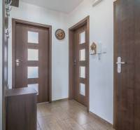 Hallway in a 3-room apartment, contains a door, a coat rack, and a clock.