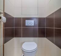 A bathroom with brown and white tiles in a 3-room apartment.