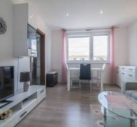 A bright living room with a table, television, and sofa in a three-room apartment.