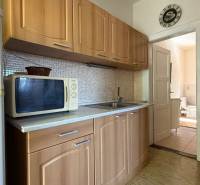 A kitchen in a family house with a microwave and a sink, next to slightly open doors to the bathroom.