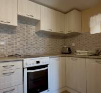 A practical kitchen in a family house with white cabinets and appliances.