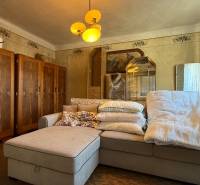 Living room in a family house with a large sofa, cabinets, vintage decorations, warm lighting.
