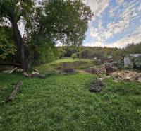 A spacious garden of a family house in Nitrianske Sučany with trees and stones.