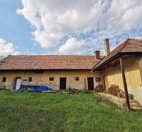 An older family house in Nitrianske Sučany surrounded by grass and wood on Nirtrianske Sučany street.