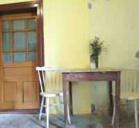 Yellow walls in a family house with a wooden table, chairs, and a small vase with flowers.