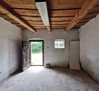 Interior of a family house with old wooden doors and ceiling beams, illuminated by a neon light.