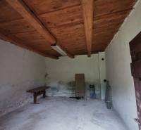 A wooden ceiling in a room of a family house with simple furnishings and white walls.