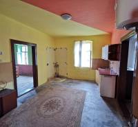 Interior of a family house with a kitchen unit and a door opening onto variously colored walls.