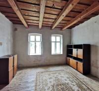 A room in a family house with a wooden ceiling, windows, cabinets, carpet on the floor.