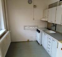 A kitchen in a studio apartment with a stove, sink, and kitchen cabinets.