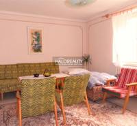 Living room in a family house, vintage furniture, carpet, light walls, large window.
