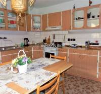 A kitchen in a family house with a wooden cabinet, a dining table, and floral decoration.