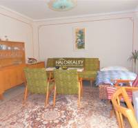 A room in a family house with wooden furniture, a carpet, and flowers in a decorative vase.