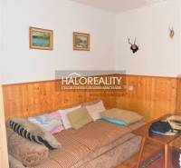 Interior of a family house with a sofa, paintings on the wall, and wooden paneling.