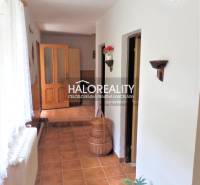 A hallway of a family house with tiles, room doors, and a basket on the floor.