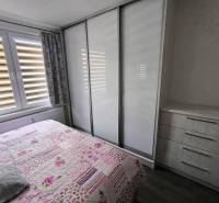A bedroom with a built-in wardrobe and a floral bedspread in a 3-room apartment.