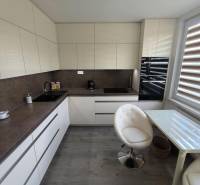 A kitchen in a 3-room apartment with light furniture, a glass table, and two chairs.
