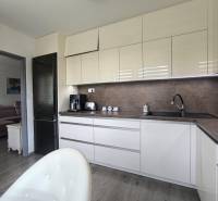 A kitchen in a 3-room apartment with modern equipment and an adjoining living room, light tones.