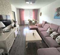 Living room in a 3-room apartment with a pink sofa, table, and decorations on the sideboard.