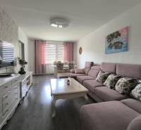 Living room with a sofa and a table in a 3-room apartment, light walls, TV on a cabinet.