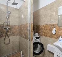 A bathroom with a shower and a washing machine in a 3-room apartment.