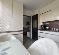A kitchen in a 3-room apartment with white cabinets and a dining table.