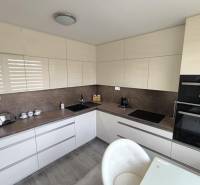 Kitchen in a 3-room apartment, modern cabinets and appliances, light shades.