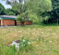 A plot for residential use in Borinka with trees and an unfinished house near the forest.