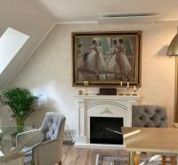 Interior of a 2-room apartment with a fireplace, a painting of dancers, and comfortable armchairs.