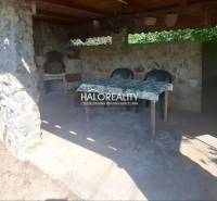 In Klížska Nemá, there is an outdoor seating area with stones and a table by a family house.