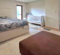 A bedroom in a family house with a double bed, a baby crib, and a light-colored floor.