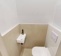 Compact toilet with a sink in a 2-room apartment, beige tiles and white wall.