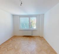 A room with parquet floors in a bright 2-room apartment, a window with a view of trees.