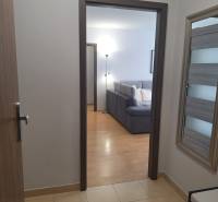 A hallway with a view of the living room in a 3-room apartment, visible couch and lamp.