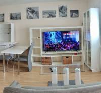 Living room in a two-room apartment with a TV, sofa, and dining table.