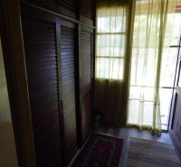 A cottage with a wardrobe, curtains, and rugs offers a cozy interior with a view.