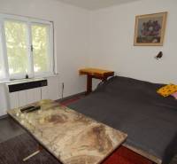 The cottage offers a cozy bedroom with a double bed, a table, and a chair.