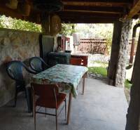Stone terrace at the cottage in Klížska Nemá with a table and chairs under a shelter.