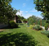 The garden of the cottage in Klížska Nemá surrounded by greenery and a blue sky.