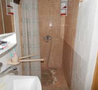 A bathroom in a cabin with brown tiles, a shower, and a sink.