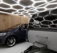 A car and a caravan inside commercial premises with lighting and wooden walls.
