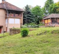 A family house in České Brezové with a landscaped garden and a wooden annex in the background.