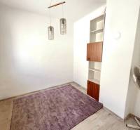 A room in a family house with a purple carpet, a wooden light fixture, and a built-in shelf.