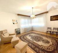Living room in a family house with an armchair, pictures on the walls, and a patterned carpet.