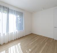 A bright room in a 3-room apartment, wooden decor flooring, large window with white curtains.