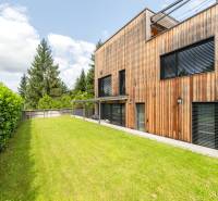 A wooden facade of a house surrounded by a well-maintained lawn and a hedge on Devínska Road.
