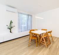 Dining table and chairs on a wooden-decor floor in a three-room apartment.