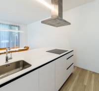 A kitchen in a 3-room apartment with a sink, a range hood, and a floor with a wooden decor.