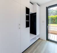 White built-in wardrobe and large window in a 3-room apartment with a wooden decor floor.